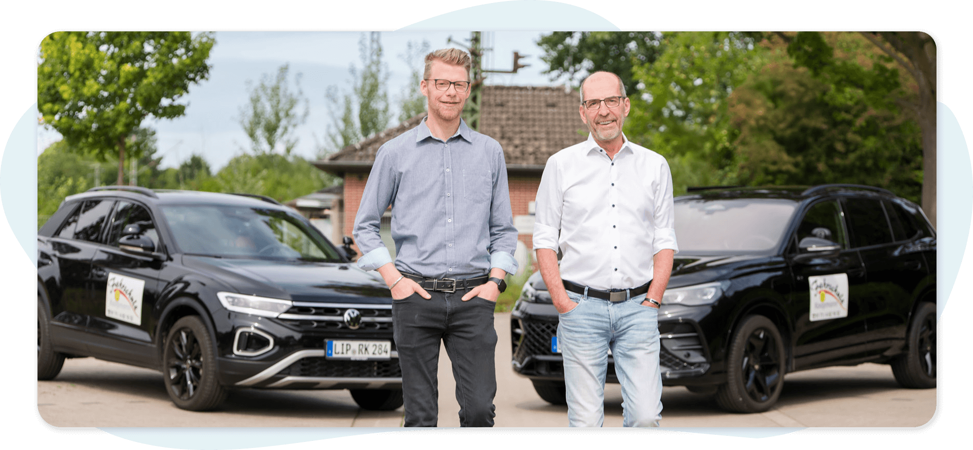 Pierre Schotte und Roger Koopmann vor zwei schwarzen Fahrschulautos auf einem Parkplaz